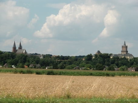 Kleve : Von weitem ist in der Niederrheinebene die Schwanenburg zu sehen. Sie wurde auf einem steil abfallenden Hügel ( Kliff ) erbaut. Links im Bild die Stiftskirche.